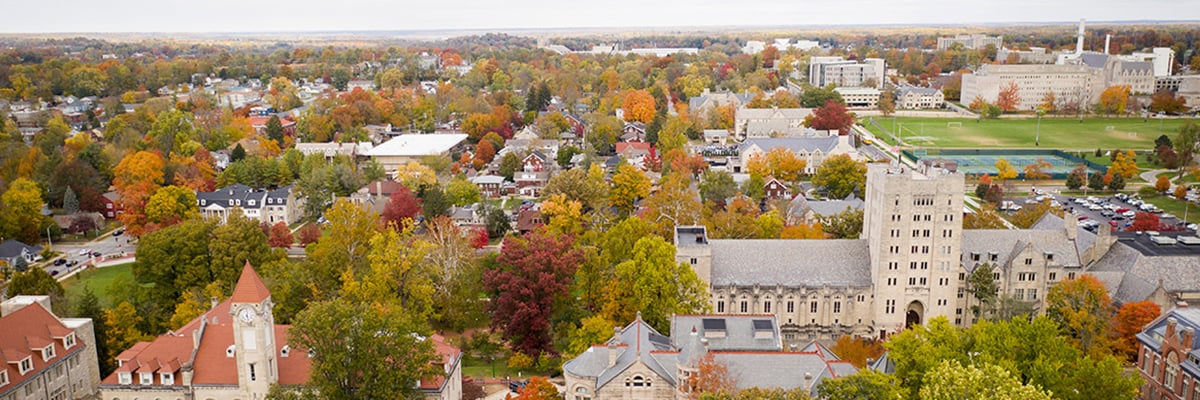 Aeriel shot of Indiana University Campus with buildings peaking through a sea of with green and brown trees